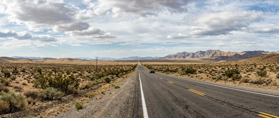 Ultra-wide panoramic shot of a desert highway stretching to horizon