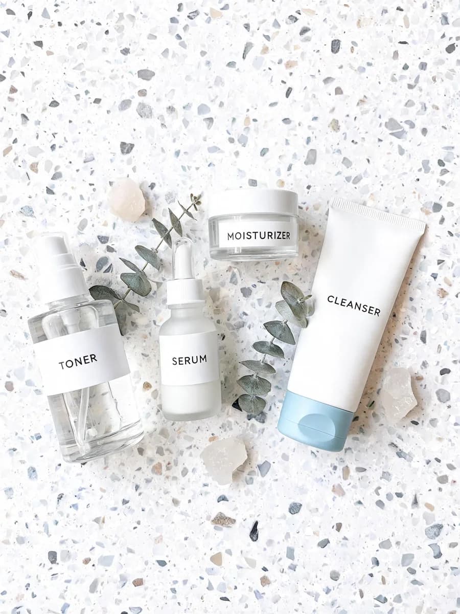 Product flatlay of skincare bottles on terrazzo surface
